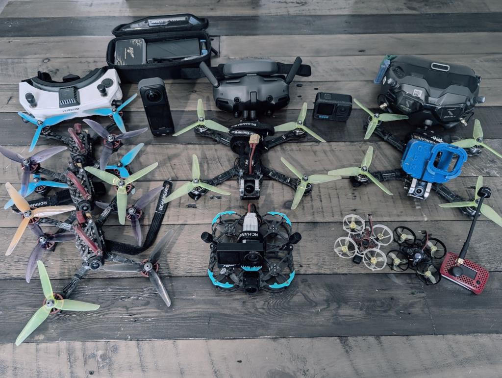FPV-Equipment auf Tisch: Naked GoPro, DJI Goggles 1 & 3, HDZero Goggle, Huma20, Racing- & Freestyle-Copter, Tiny Whoops – professionelle FPV-Drehs in Hamburg werbe-und-imagefilme